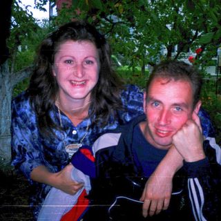 Two people smiling outdoors at night.