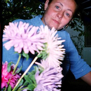 Woman holding large pink flowers indoors.