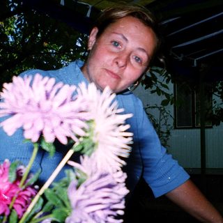 Woman holding large pink flowers indoors.