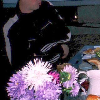 Three people dining outdoors at a table with food and drinks.