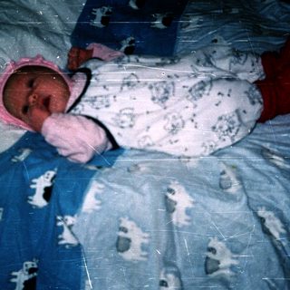 Newborn baby wearing pink hat and onesie.