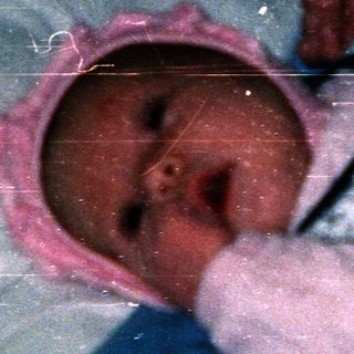 Newborn baby wearing pink hat and onesie.