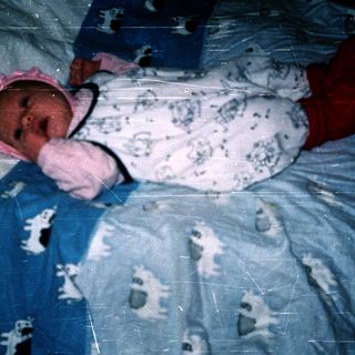 Newborn baby wearing pink hat and onesie.