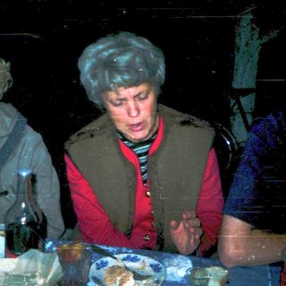 Three people gathered indoors, eating and drinking.