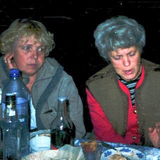 Three people gathered indoors, eating and drinking.