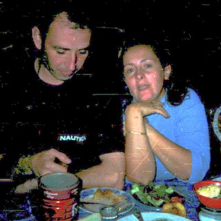 Three people dining together indoors at night.