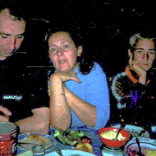 Three people dining together indoors at night.