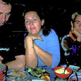 Three people dining together indoors at night.