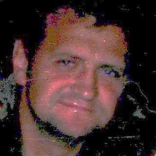 Man sitting indoors at night, blurred lighting.