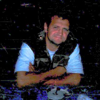 Man sitting indoors at night, blurred lighting.