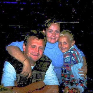 Family enjoying wet outdoor nighttime activity together.