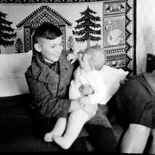 Two boys playing indoors with a stuffed animal.