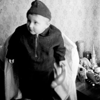 Young child in vintage clothing holding pipe.