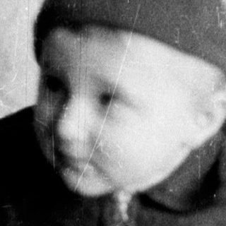 Young child in vintage clothing holding pipe.