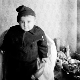 Young child wearing knitted hat and sweater indoors.