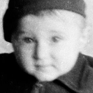 Young child wearing knitted hat and sweater indoors.