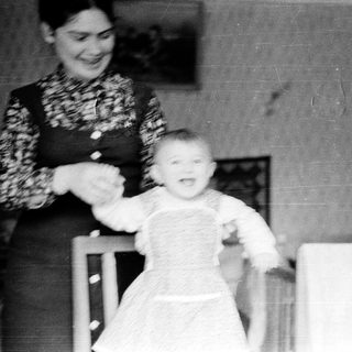 A woman holding a baby walking indoors.