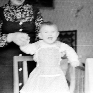 A woman holding a baby walking indoors.