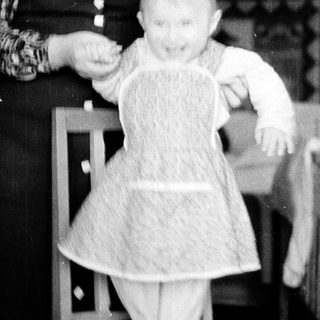 A woman holding a baby in a dress.