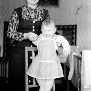 A woman holding a baby in a dress.