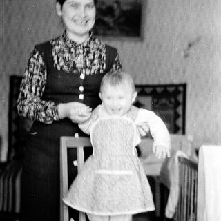 A woman holding a baby in a dress.