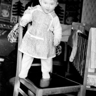 Young child in winter clothing holding mittens.