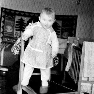 Young child in winter clothing holding mittens.