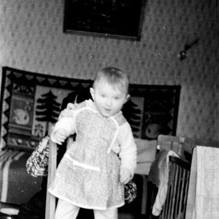 Young child in winter clothing holding mittens.