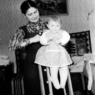 A woman holding a young child in a high chair.