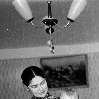 A woman holding a young child in a high chair.