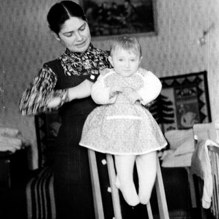 A woman holding a young child in a high chair.