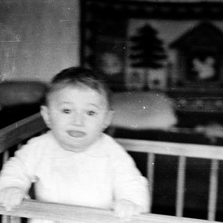Baby sitting in a crib indoors.