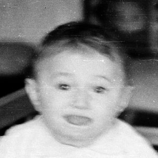 Baby sitting in a crib indoors.