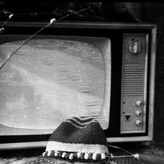 Vintage television with fuzzy screen, knit hat on stand.