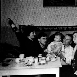 Family gathering with baby indoors, mid-20th century.