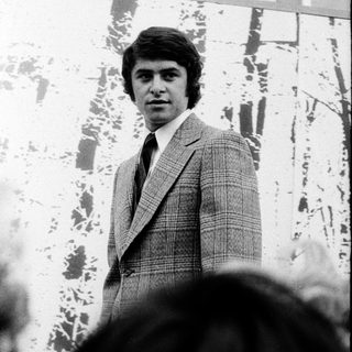 Young man in 1970s-style suit posing outdoors.