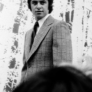 Young man in 1970s-style suit posing outdoors.