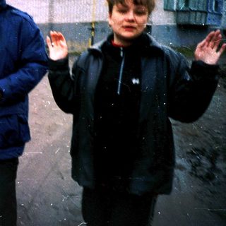 Three people standing outside in light rain.