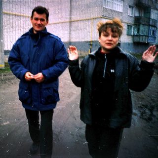 Three people standing outside in light rain.