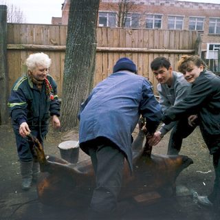 People lifting a heavy metal object outdoors.