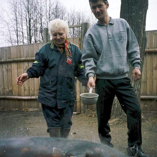 Two people skinning a large animal outdoors.
