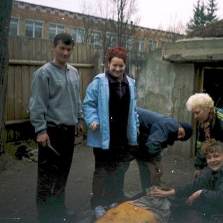 Four people posing outdoors in wet, muddy area.