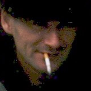 Man smoking outdoors near rustic water container.
