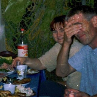Group of men enjoying meal outdoors under tent.