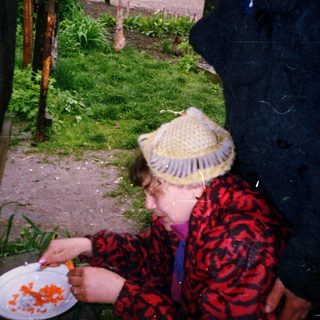 Two people eating outside near a window.