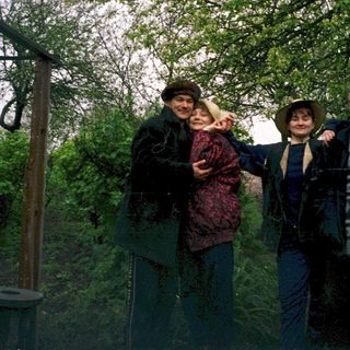 Four people posing outdoors near a wooden structure.
