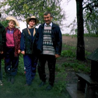 Four people posing outdoors in a rural setting.