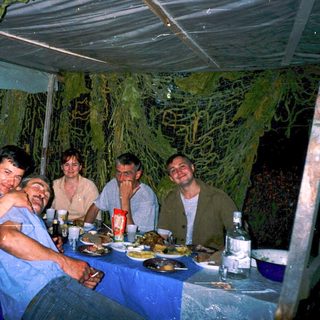 Group enjoying dinner outdoors under rain.