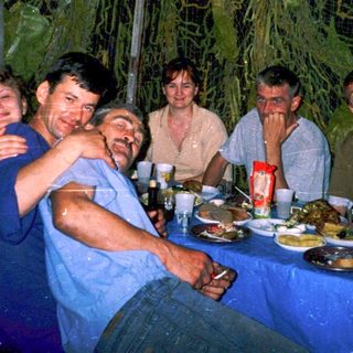 Group enjoying dinner outdoors under rain.