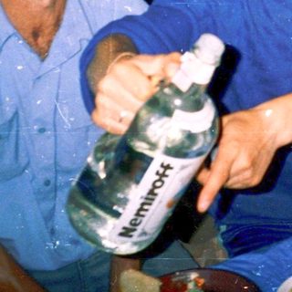 Three men sharing a meal indoors with homemade food and drinks.